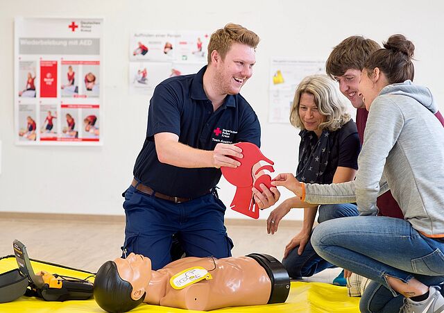 Ein Erste Hilfe Ausbilder zeigt Kursteilnehmern ein Kopfmodell