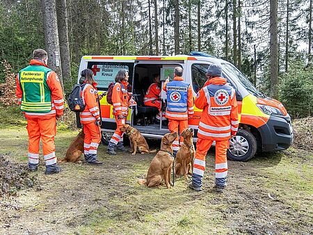 Hund-Mensch-Teams der Rettungshundestaffel beim Einsatzfahrzeug