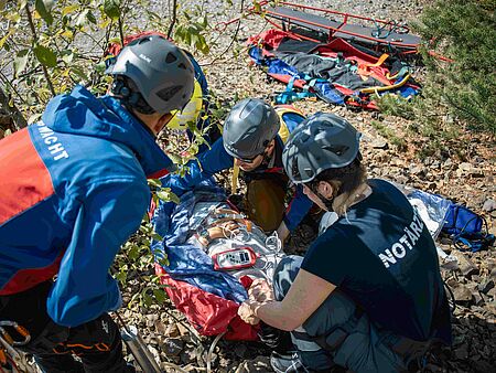 Bergretter und eine Notärztin versorgen einen Patienten am Berg