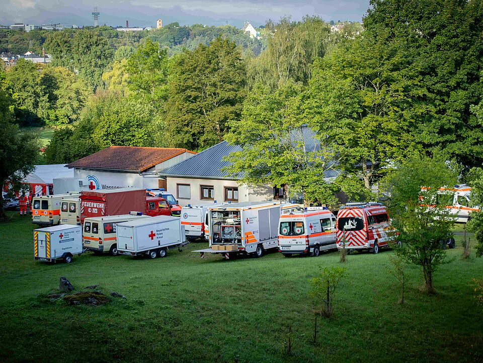Fahrzeuge des BRK und der Feuerwehr stehen hinter den Gebäuden am Lettenbachsee