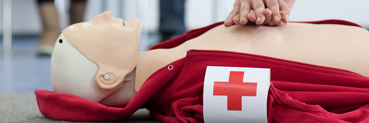 Hände drücken auf eine Übungspuppe zur Wiederbelebung