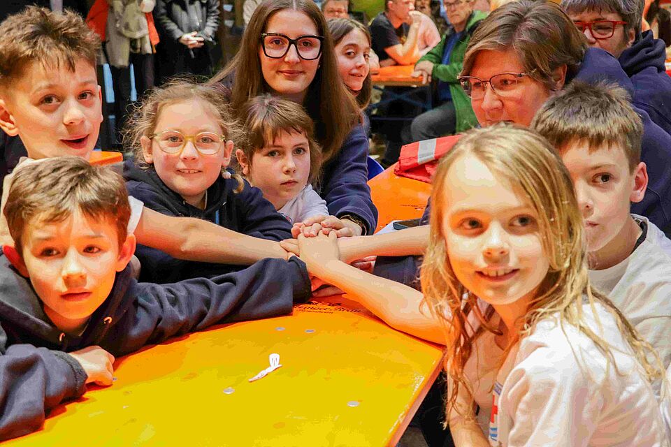 Kinder sitzen an einem Tisch und halten die Hände aufeinander