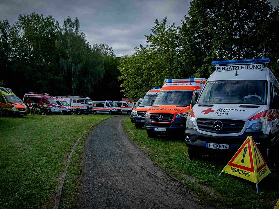 Zahlreiche Einsatzfahrzeuge des BRK stehen auf einer Wiese