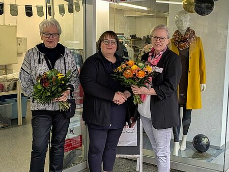 Die beiden Mitarbeiterinnen des Kleiderladens bekommen vor dem Laden einen Blumenstrauß überreicht
