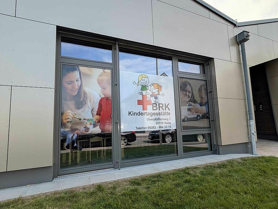 Das gebäude von außen mit dem Logo der Kita
