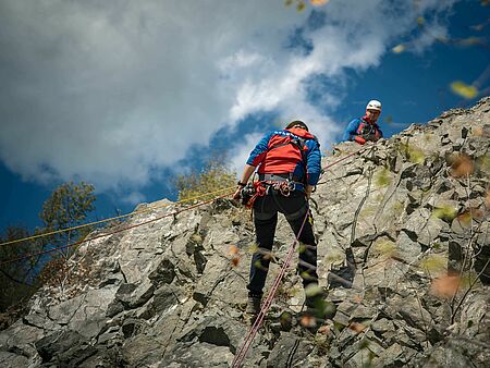Ein Retter der Bergwacht seilt sich an der Felswand ab