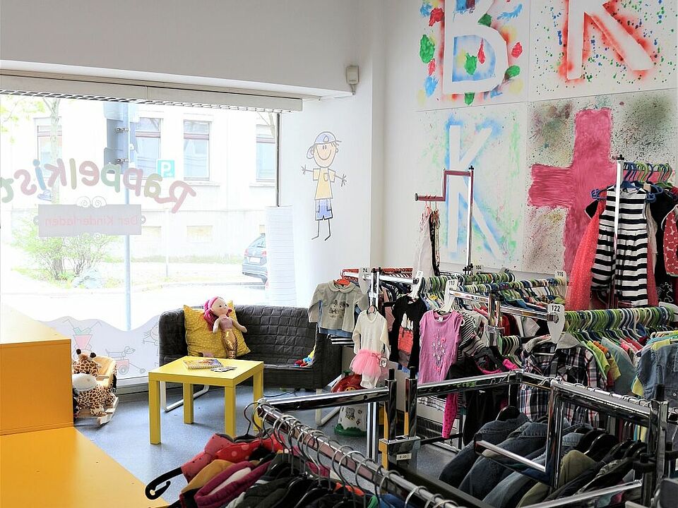 Blick über Kleiderständer zum Schaufenster im Kleiderladen