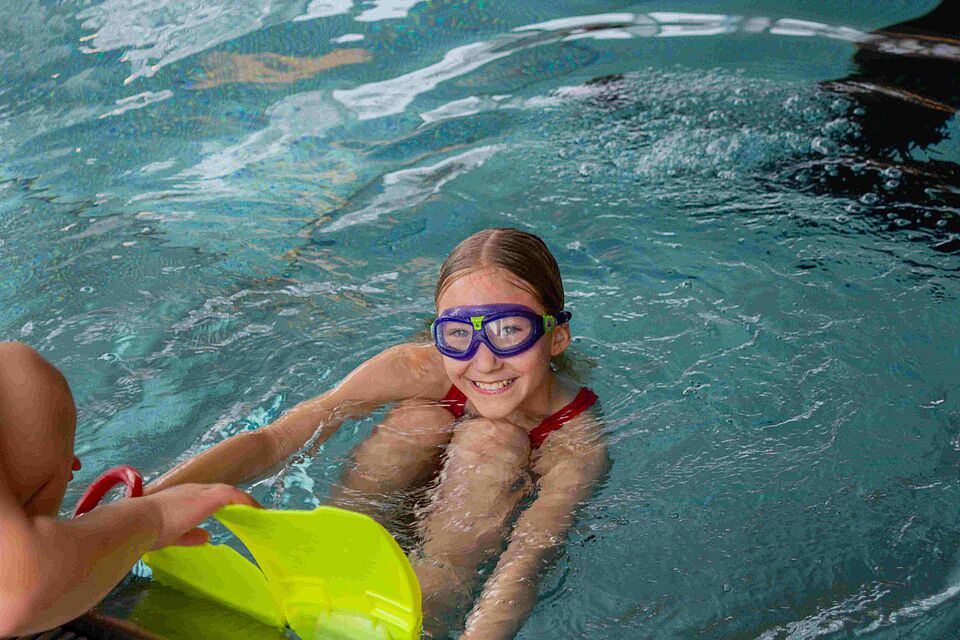 Ein Mädchen hält sich am Beckenrand des Schwimmbeckens fest