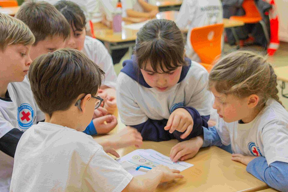 Kinder sitzen an einem Tisch und lösen Aufgaben