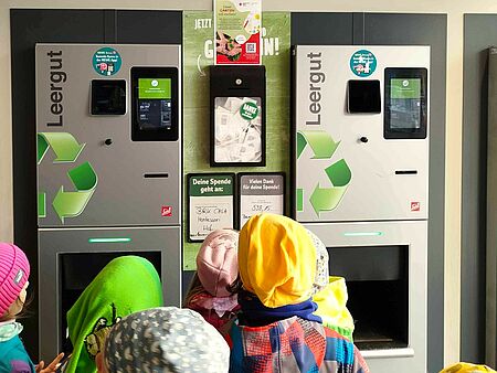 Kinder der Kita BRKcasa Montessori stehen vor dem Pfandautomaten