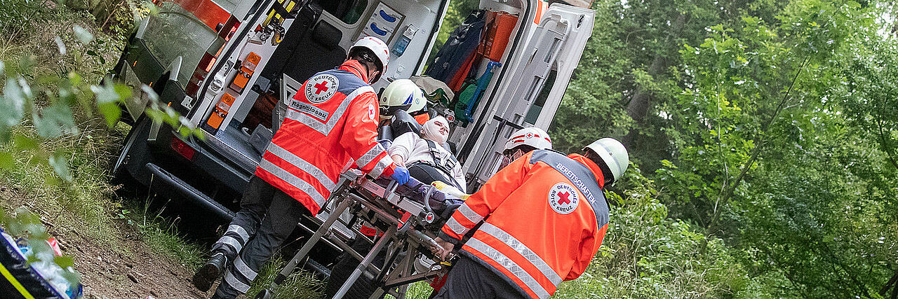 BRK-Sanitäter verbringen einen Verletzten auf einer Trage in den Rettungswagen