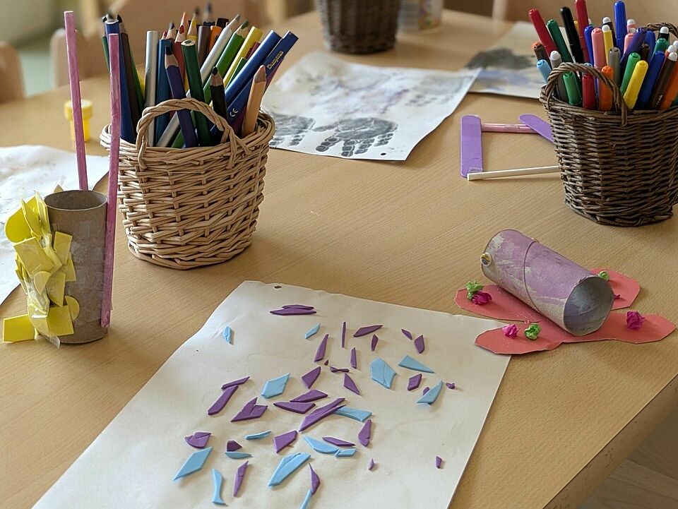 Buntstifte und gemalte Bilder liegen auf dem Tisch