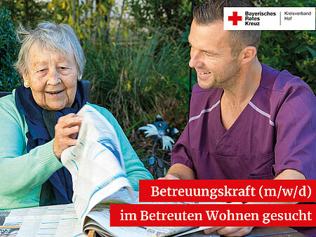 Eine alte Dame liest zusammen mit einem Betreuer die Zeitung