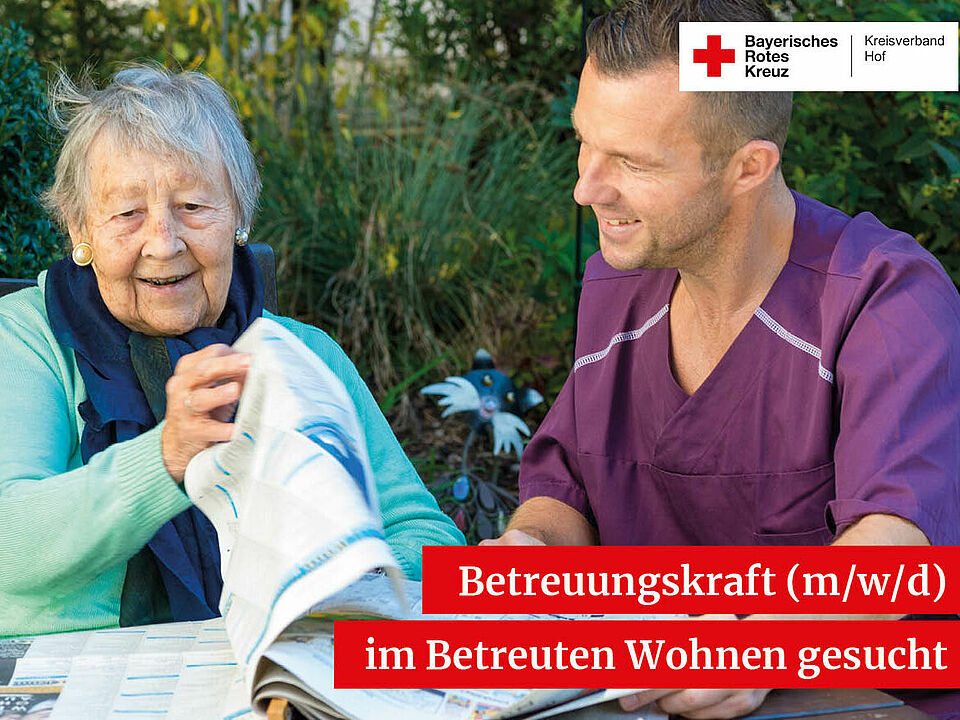 Eine alte Dame liest zusammen mit einem Betreuer die Zeitung